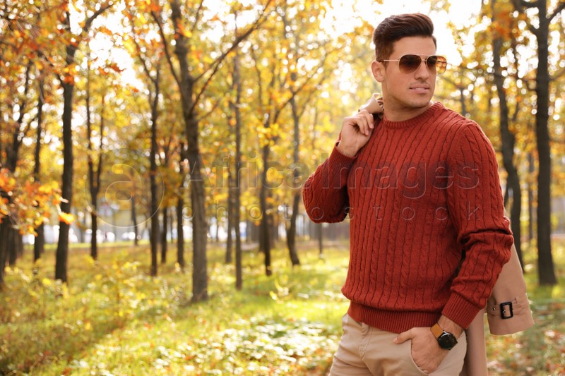 Handsome man walking in park on autumn day