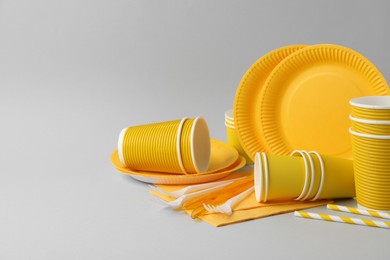 Disposable tableware on light grey background. Space for text