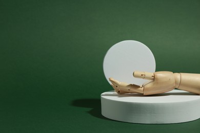 Photo of Product photography props. Round shaped podiums and wooden mannequin hand on green background, space for text