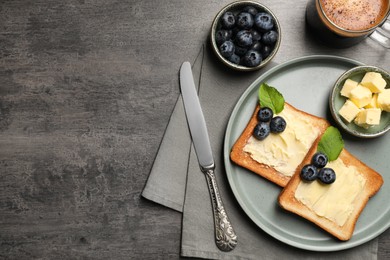 Delicious toasts served with butter, blueberries and coffee on grey wooden table, flat lay. Space for text