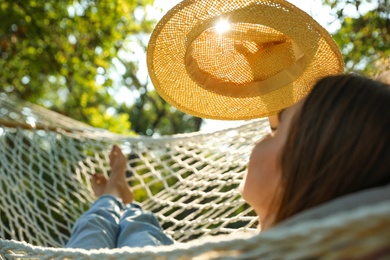 Young woman with hat resting in comfortable hammock at green garden, closeup