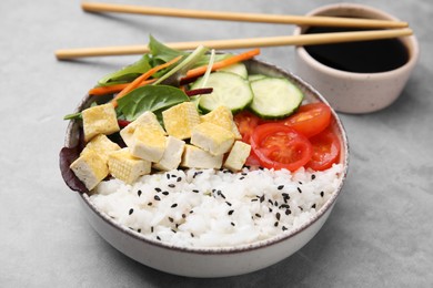 Photo of Delicious poke bowl with vegetables, tofu and mesclun served on light grey table, closeup
