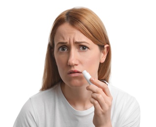 Upset woman with herpes applying lip balm against white background