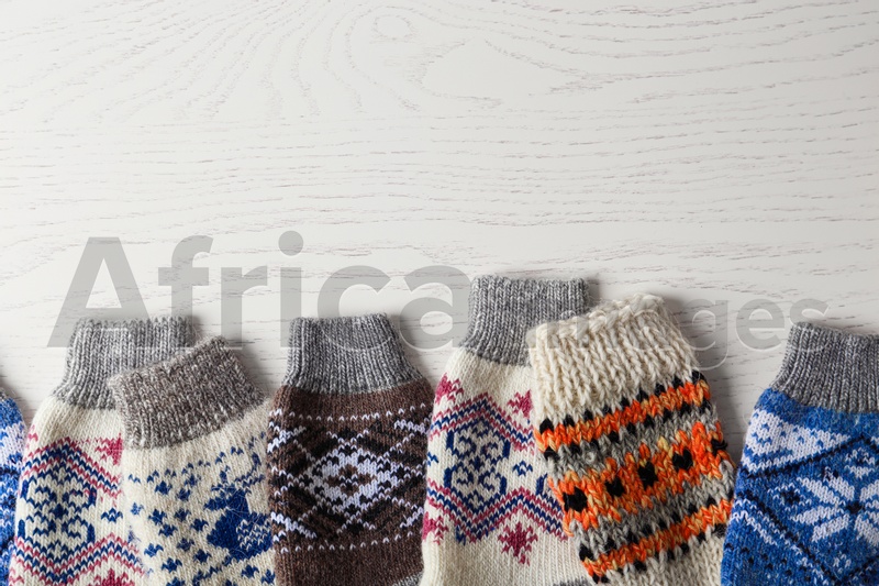 Soft knitted socks on white wooden background, flat lay with space for text. Winter clothes