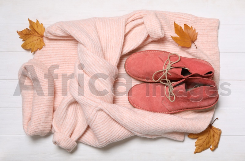 Photo of Flat lay composition with sweater and dry leaves on white wooden background. Autumn season