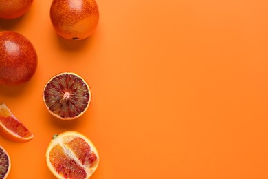 Many ripe sicilian oranges on orange background, flat lay. Space for text