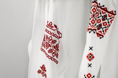 Beautiful shirts with different embroidery designs on white background, closeup. Ukrainian national clothes