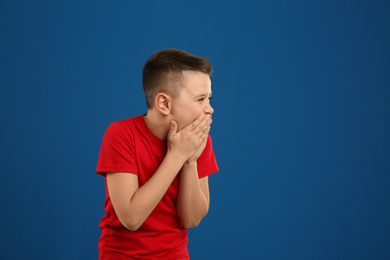 Portrait of laughing preteen boy on blue background, space for text