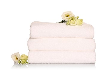 Folded soft terry towels with beautiful flowers on white background