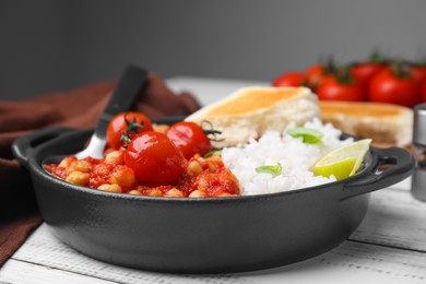 Delicious chickpea curry with rice on white wooden table, closeup