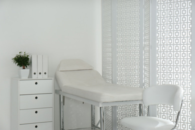 Examination room with modern couch and folding screen in clinic