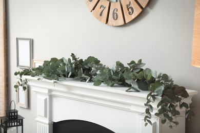 Beautiful garland with eucalyptus branches on mantelpiece in room