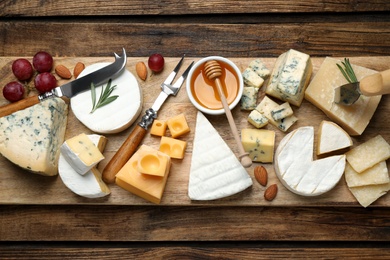 Flat lay composition with different sorts of cheese and knives on wooden table
