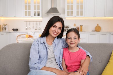 Photo of Portrait of happy mother and daughter on sofa at home. Single parenting