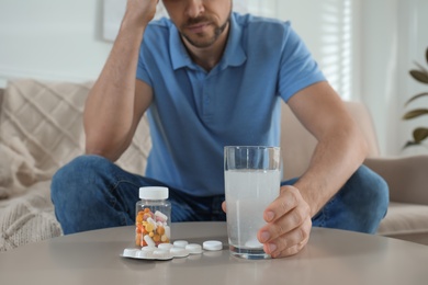 Man taking medicine for hangover at home, closeup