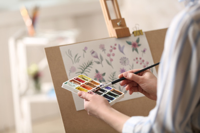 Woman painting flowers with watercolors in workshop, closeup