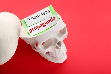 Photo of Information warfare concept, media propaganda influence. Paper card inside human skull on red background, space for text