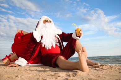 Santa Claus with cocktail relaxing on beach. Christmas vacation