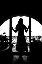 Image of Silhouette of woman standing on balcony, back view