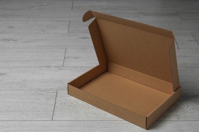 Photo of Empty open cardboard box on floor, space for text