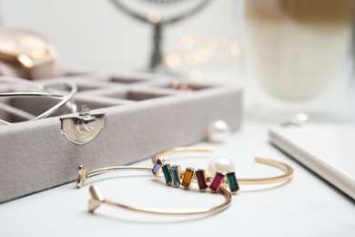Beautiful bracelets and jewelry box on white table, closeup