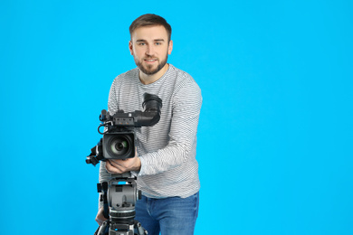 Operator with professional video camera on blue background, space for text