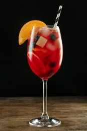 Glass of Red Sangria on wooden table against black background