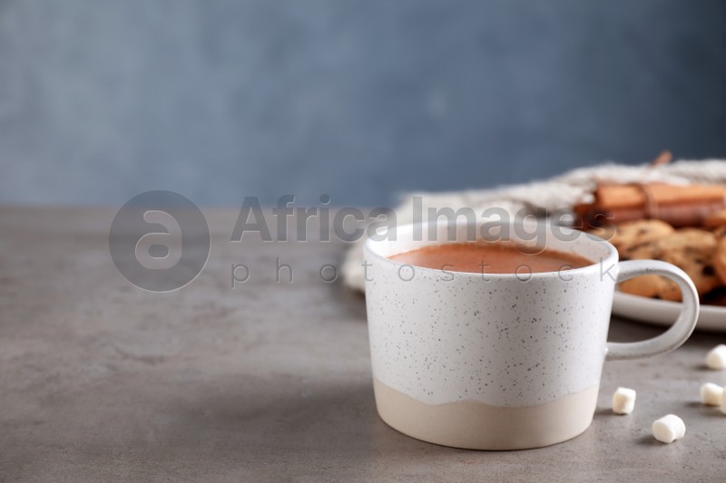 Cup of delicious hot cocoa on grey table, space for text
