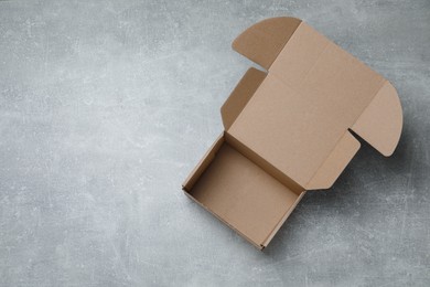 Photo of Empty open cardboard box on grey table, top view. Space for text