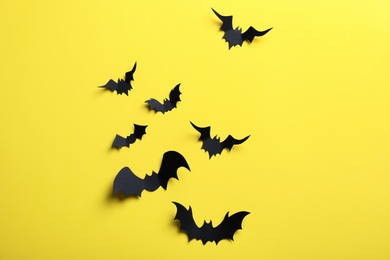 Paper bats on yellow background, flat lay. Halloween decor