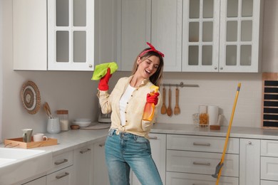 Woman with spray bottle and rag singing while cleaning at home