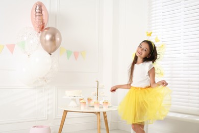 Cute little girl wearing fairy costume with wings in decorated room. Space for text