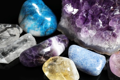 Photo of Different beautiful gemstones on black background, closeup