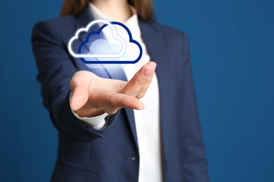 Woman holding virtual clouds icon on blue background, closeup of hand. Data storage concept