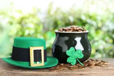 Green leprechaun hat and pot with gold coins on wooden table. St Patrick's Day celebration