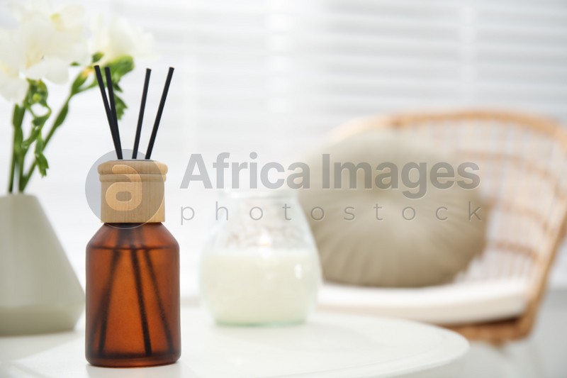 Reed diffuser and home decor on white table in room. Space for text