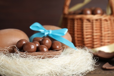 Tasty chocolate eggs with candies in decorative nest, closeup