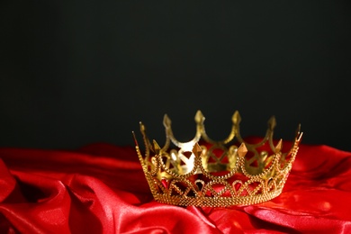 Photo of Beautiful golden crown on red fabric. Fantasy item