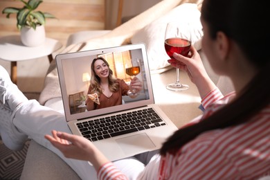Woman with glass of wine having online party via laptop at home during quarantine lockdown, closeup