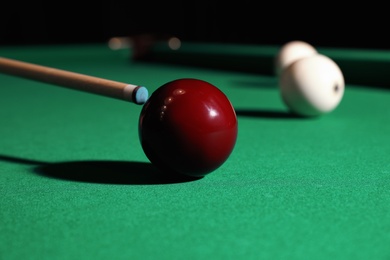 Striking red billiard ball with cue on table