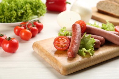 Delicious vegetarian sausages with lettuce and tomatoes on white wooden table