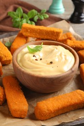 Delicious chicken nuggets and cheese sauce with basil on table, closeup