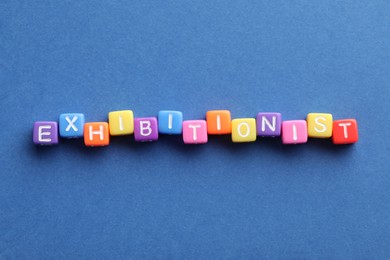Photo of Word EXHIBITIONIST made with colorful cubes on blue background, flat lay