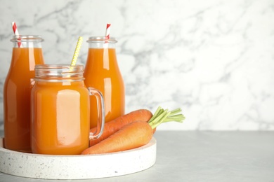 Freshly made carrot juice on white table, space for text
