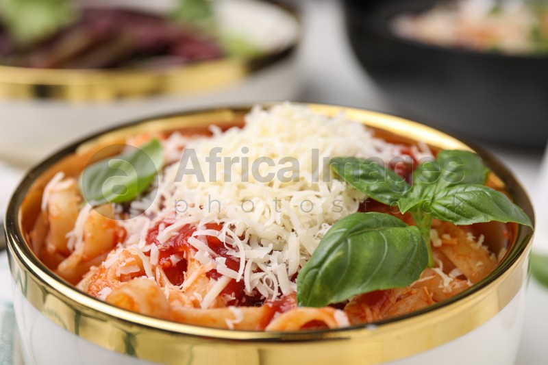 Delicious pasta with tomato sauce, basil and parmesan cheese in bowl, closeup