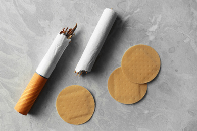 Nicotine patches and broken cigarettes on grey table, flat lay