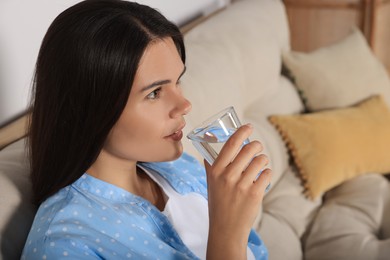 Young woman drinking water indoors. Refreshing drink