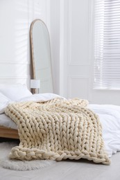 Soft chunky knit blanket on bed in stylish room interior