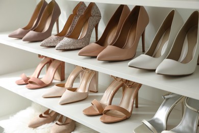Different stylish women's shoes on shelving unit