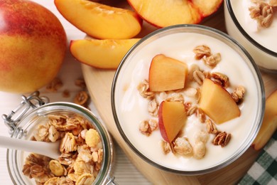 Delicious yogurt with fresh peach and granola on white table, flat lay